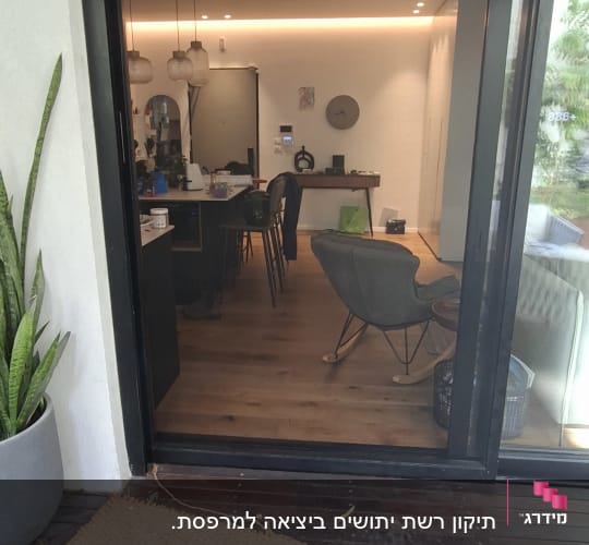 דלת זכוכית פתוחה עם נוף לסלון מודרני